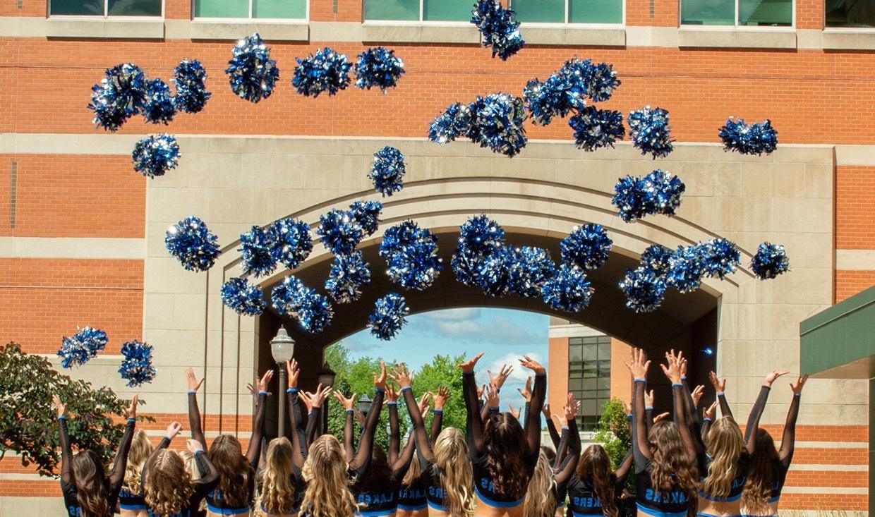 Dance team throws pom-poms towards the sky in celebration